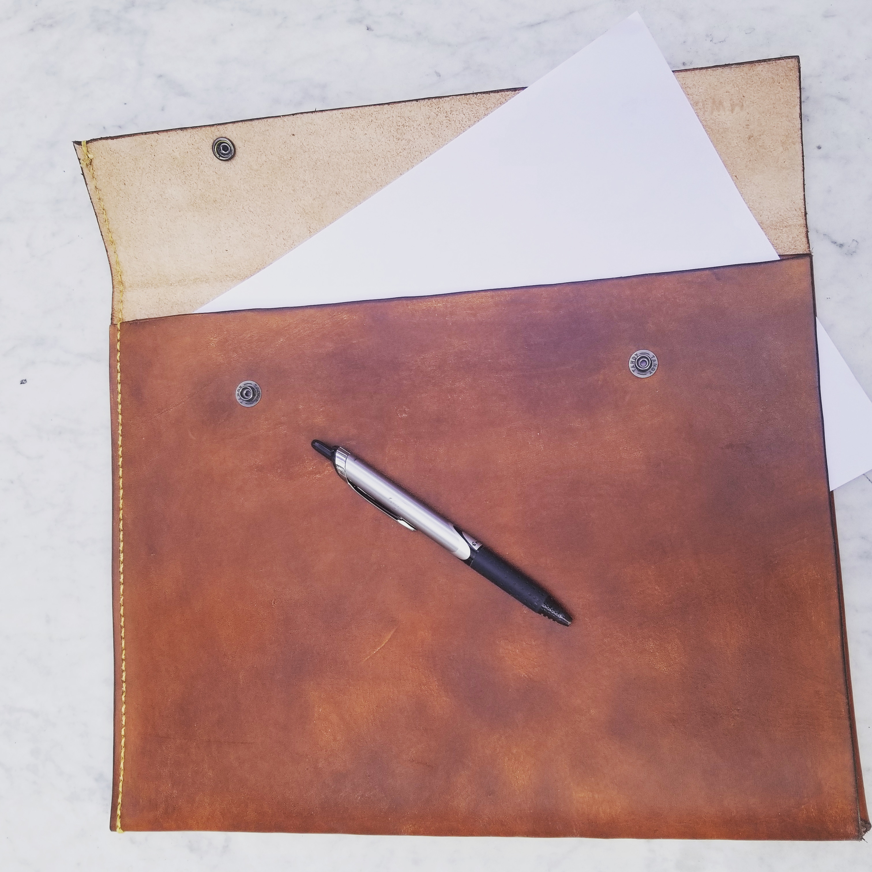 Full view of the JM IV handmade leather portfolio open with paper and a pen